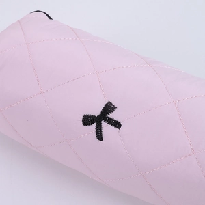 Macro shot of pink quilted pencil case featuring a black bow embroidery detail