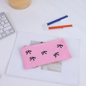 Dettaglio dell'astuccio in tela rosa con fiocchi neri su una scrivania da ufficio