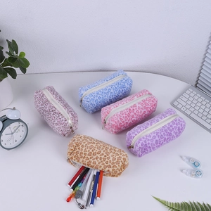 Vue détaillée de trousses à crayons en peluche léopard colorées sur un bureau blanc