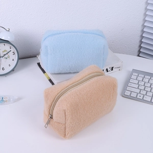 Detail of plush cream-colored stationery pouches in blue and camel with metal zippers