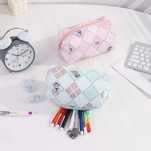 Quilted pouch with cute bear patterns storing pens on a white desk with office props