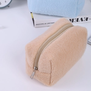 Detail of plush cream pencil case with fuzzy texture and silver zipper on white desk