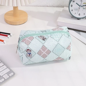 Detailed view of a green checkered stationery pouch with cute cartoon animal patterns