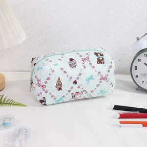 Close-up of a green quilted pencil case with cute bear and dessert prints on a desk