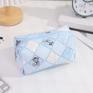 Detailed view of light blue quilted fabric pencil case with cute bear and book patterns