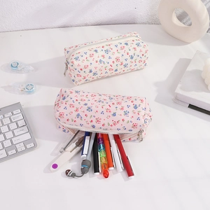 Detail of floral canvas pencil cases in cream and pink colors on a bright desk