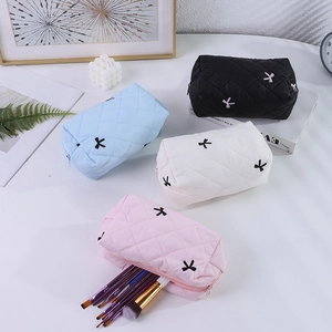 Détail de trousses à maquillage matelassées avec nœuds et rangement pour pinceaux