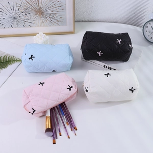Détail de trousses de maquillage matelassées avec broderie nœud et espace pinceaux