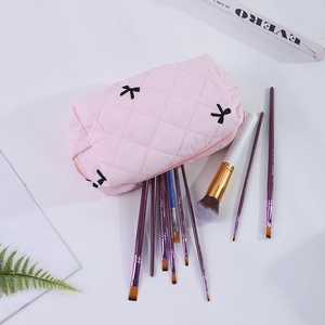 Détail d'une trousse à maquillage matelassée rose avec broderies nœuds et fermeture éclair