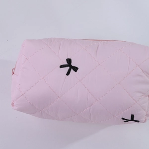 Détail macro de la trousse de maquillage rose matelassée avec broderies petits nœuds noirs