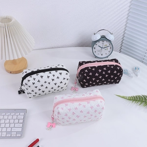 Quilted bow cosmetic bag set with metal zippers and cute pearl charms on desk