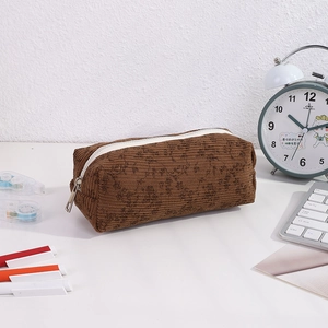 Brown floral corduroy pencil case with white zipper shown in a desk workspace setup