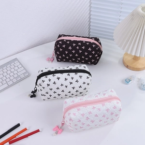 Detail of three makeup bags with bow prints, quilted texture, and pearl zipper charms