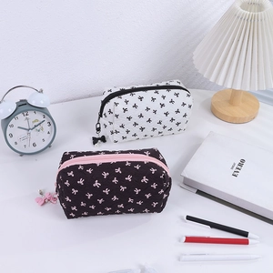Detail of bow-print makeup bags with textured fabric and pearl bow zipper pullers