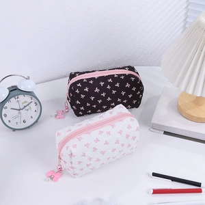 Detail of quilted cosmetic bag with pink bow prints and decorative zipper pull