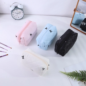Gros plan de trousses à maquillage matelassées à nœuds en quatre couleurs avec fermeture