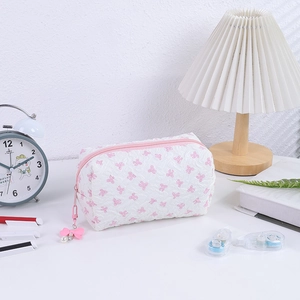 Close-up of quilted cosmetic bag featuring pink bows and a pearl zipper charm