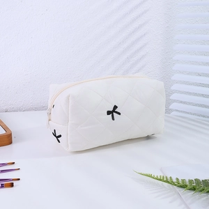 Détail de la trousse cosmétique matelassée avec broderie de nœud noir et fermeture éclair