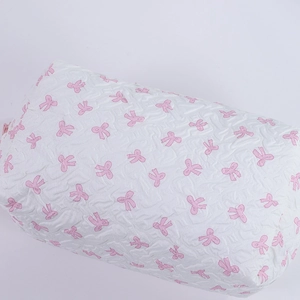 Detail of white makeup bag with pink bow pattern and quilted bubble texture fabric