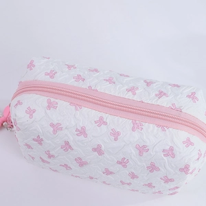 Detail of pink bow pattern fabric and pearl zipper charm on white cosmetic bag