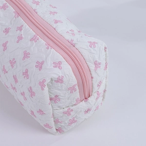 Close-up of quilted cosmetic bag with pink bow patterns and a matching zipper