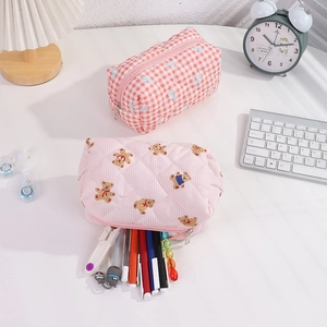 Vue détaillée de trousses matelassées à ours avec stylos colorés sur bureau rose