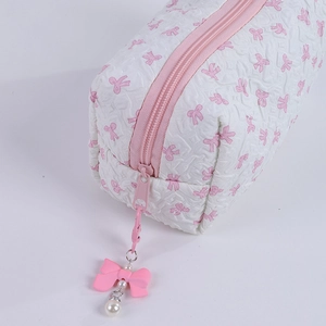 Close-up of white quilted makeup bag with pink bows and pearl zipper detail