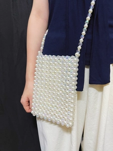 Elegant white faux pearl and crystal woven crossbody bag worn by a model in a close-up