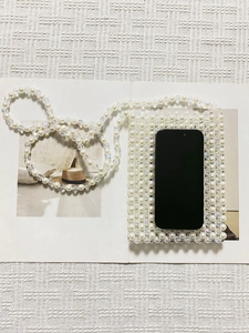 Elegant pearl and crystal woven mini crossbody bag for cell phones on magazine backdrop