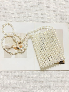 Elegant handmade mini crossbody pearl bag with colorful beads on a white knit surface