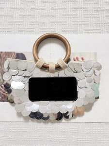 Details der silbernen Pailletten-Abendtasche mit rundem Holzgriff und Perlenstickerei