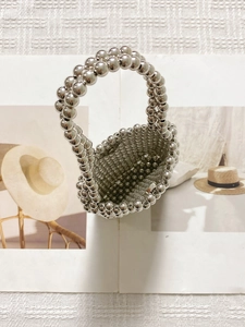 Handmade silver beaded tote bag with metallic sheen on a fashion magazine background