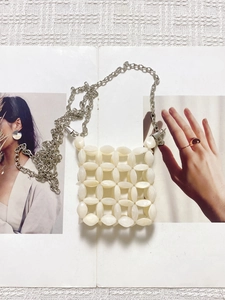 Handmade cream white beaded crossbody bag with silver metal chain on fashion magazine