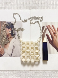 Close-up of cream handmade beaded crossbody bag with hollow weave and silver chain