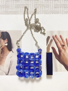 Detail of blue marbled beads and silver chain strap on a mini woven crossbody bag