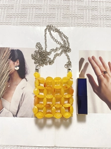 Macro detail of handmade yellow beaded mini bag with silver chain and lipstick for scale