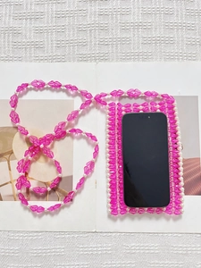 Sac de téléphone en perles roses et blanches sur un magazine ouvert au style moderne
