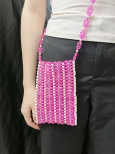 Sac bandoulière en perles acryliques roses et perles nacrées porté par un mannequin