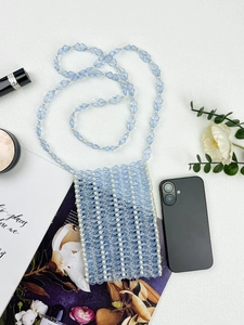 Détail du sac de téléphone en perles bleu clair avec texture croisée et longue lanière