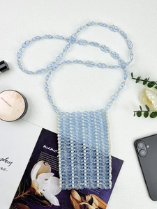 Détail d'un sac de téléphone artisanal perlé avec des perles de cristal bleu clair et blanc