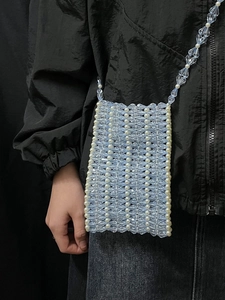 Détail du petit sac bandoulière en perles acryliques bleu clair et blanc sur modèle
