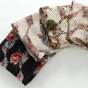 Detailed view of floral pleated chiffon scarves with accordion folds and rolled edges