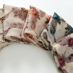 Close-up of plissé textured summer scarves featuring elegant floral prints in multi-colors