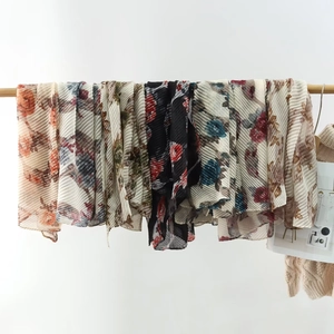 Detailed view of vertically pleated floral scarves hanging on a wooden rod for display
