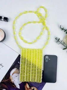 Vue détaillée du sac bandoulière en perles jaunes fait main près d'un smartphone
