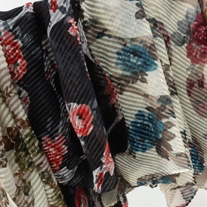 Detail of pleated floral scarf fabric with red and blue patterns on light voile