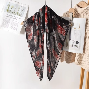 Black plisse scarf with red floral print hanging on a wooden hanger for summer beachwear