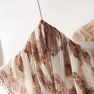Detail of lightweight pleated scarf with vintage brown floral patterns on beige voile