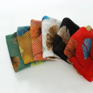 Detail view of colorful pleated ginkgo leaf print scarves in various vibrant summer colors