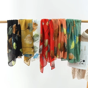 Detail of pleated summer scarves featuring artistic ginkgo leaf prints in various vibrant colors